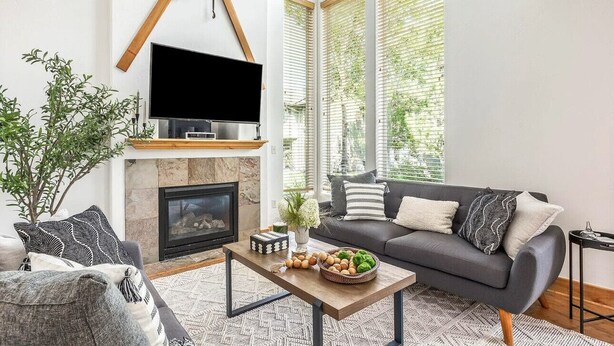 Una sala de estar moderna con chimenea, un sofá, una mesa de centro y un televisor.