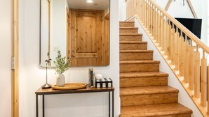 Una escalera de madera con barandilla y una puerta de madera con un espejo encima.