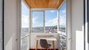 A balcony with a table and chair, a wooden ceiling, and a city view. - Solmar Sunset Place | Marina View (Ponta Delgada)