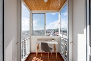 Un balcon avec une table et une chaise, un plafond en bois et une vue sur la ville.