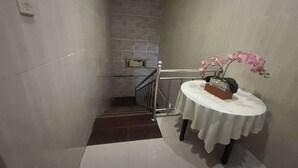 A hallway with a staircase, a small table with a vase of flowers, and a sign on the wall. - OYO 95075 Matoorstay Syariah (Pogung Lor)