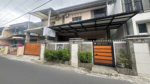 A two-story building with a covered entrance, a gated driveway, and a balcony with railings. - OYO 95075 Matoorstay Syariah (Pogung Lor)