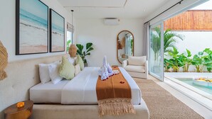 A modern hotel room with a large bed, a seating area, and a view of the ocean. - Villa Arlo Canggu (Cemagi)