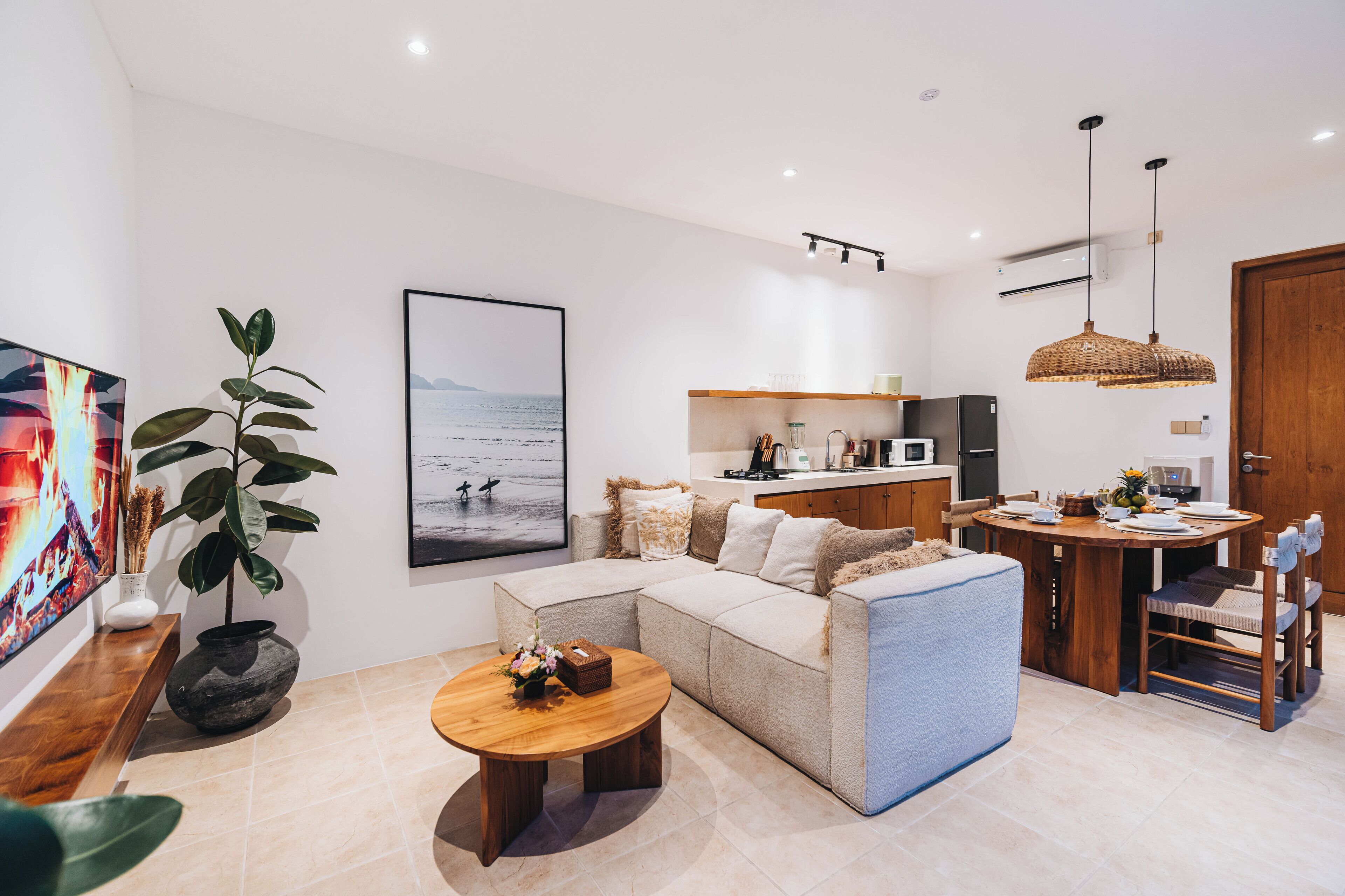 A modern living room with a sofa, coffee table, and a dining area with a table and chairs.