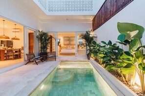 A modern house with a swimming pool, a dining area, and a living room with a sofa and a TV. - Villa Arlo Canggu (Cemagi)