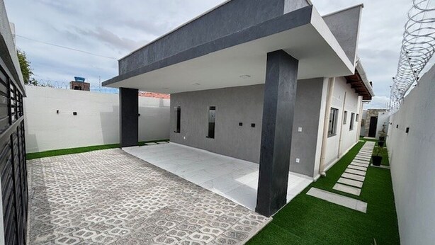A modern house with a covered patio, a patterned driveway, and a small garden area.
