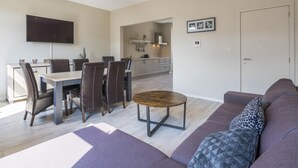 Uma sala de estar moderna com sofá, mesa de centro e um espaço de jantar com cadeiras e mesa.
