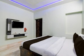 A modern hotel room with a large bed, a flat-screen TV mounted on a wall, and a small table with a vase of flowers. - Hotel O Chinar Park Kolkata Zapper (Barasat)