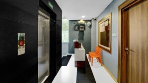 A hallway with a marble floor, an elevator, a reception desk, and a wooden door labeled "101". - Collection O Bhel Piplani Bhopal (Bhopal)
