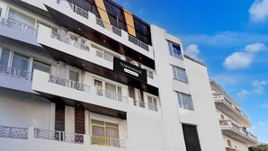 A multi-story building with balconies, a sign reading "TOWNHOUSE," and a clear blue sky. - Townhouse Railway Road Katrathe Amro (Reasi)