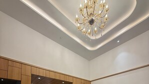 Een receptiegedeelte met een houten paneelwand, een receptiebalie, een kroonluchter, een bank en vloertegels met een patroon.