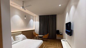 Een moderne hotelkamer met een groot bed, een bureau, een stoel, een televisie en een plafondventilator.