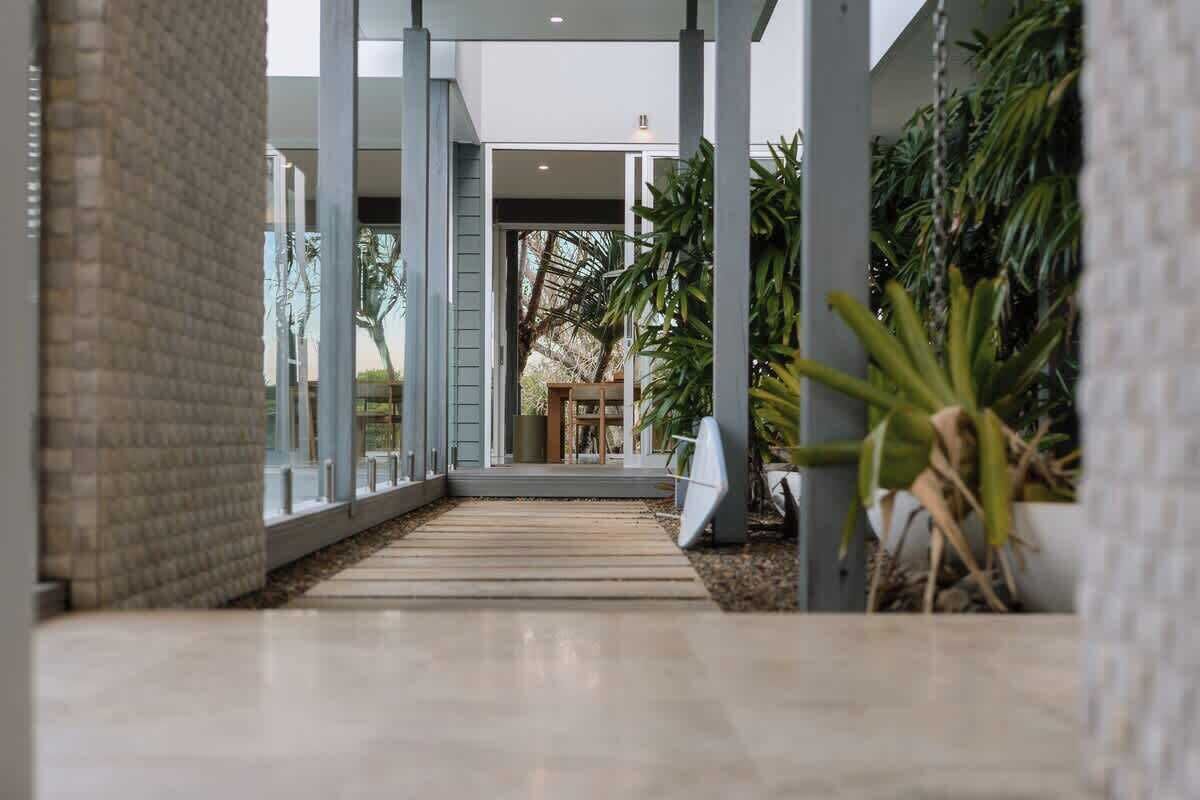 A modern building with a covered walkway, large windows, and indoor plants.