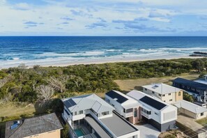 A coastal residential area with modern houses featuring solar panels, a swimming pool, and a view of the ocean. - Dune House (Tweed)