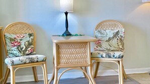 A room with two wicker chairs with floral upholstery, a small table with a lamp, and a framed picture on the wall. - Island-Inspired Cozy Retreat - Free WIFI (Honolulu)