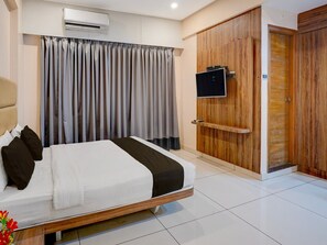 A modern hotel room with a bed, curtains, a TV, and a wooden wardrobe. - Townhouse Seetharam Palya Metro Station (Bengaluru)