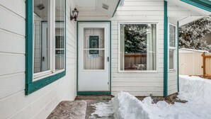 Une maison à l’extérieur blanc, avec des bordures bleu sarcelle, une porte d’entrée et un petit porche.
