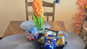 Una mesa de comedor de madera con posavasos grises, una planta en maceta y aperitivos.