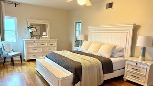 Ein Schlafzimmer mit einem großen Bett, einem Schminktisch, einem Stuhl und einem Nachttisch.