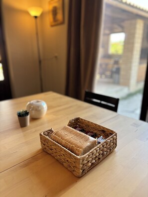 A wooden table with a woven basket containing a loaf of bread and a small potted plant. - Papyrise Oliveside (Heraklion)