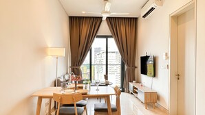Habitación de hotel moderna con zona de comedor, televisión de pantalla plana y vistas a la ciudad.