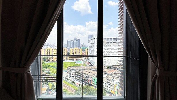 Una habitación con un ventanal grande, cortinas, un sofá y vistas a la ciudad.