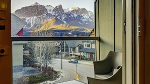 Blick aus einem Fenster auf eine Straße mit Gebäuden und einem Gebirge.