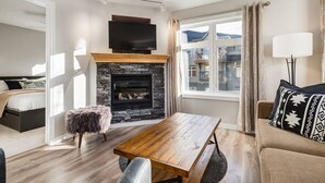 Ein modernes Wohnzimmer mit Kamin aus Stein, einem Holztisch, einer Couch und einem Fernseher über dem Kamin.