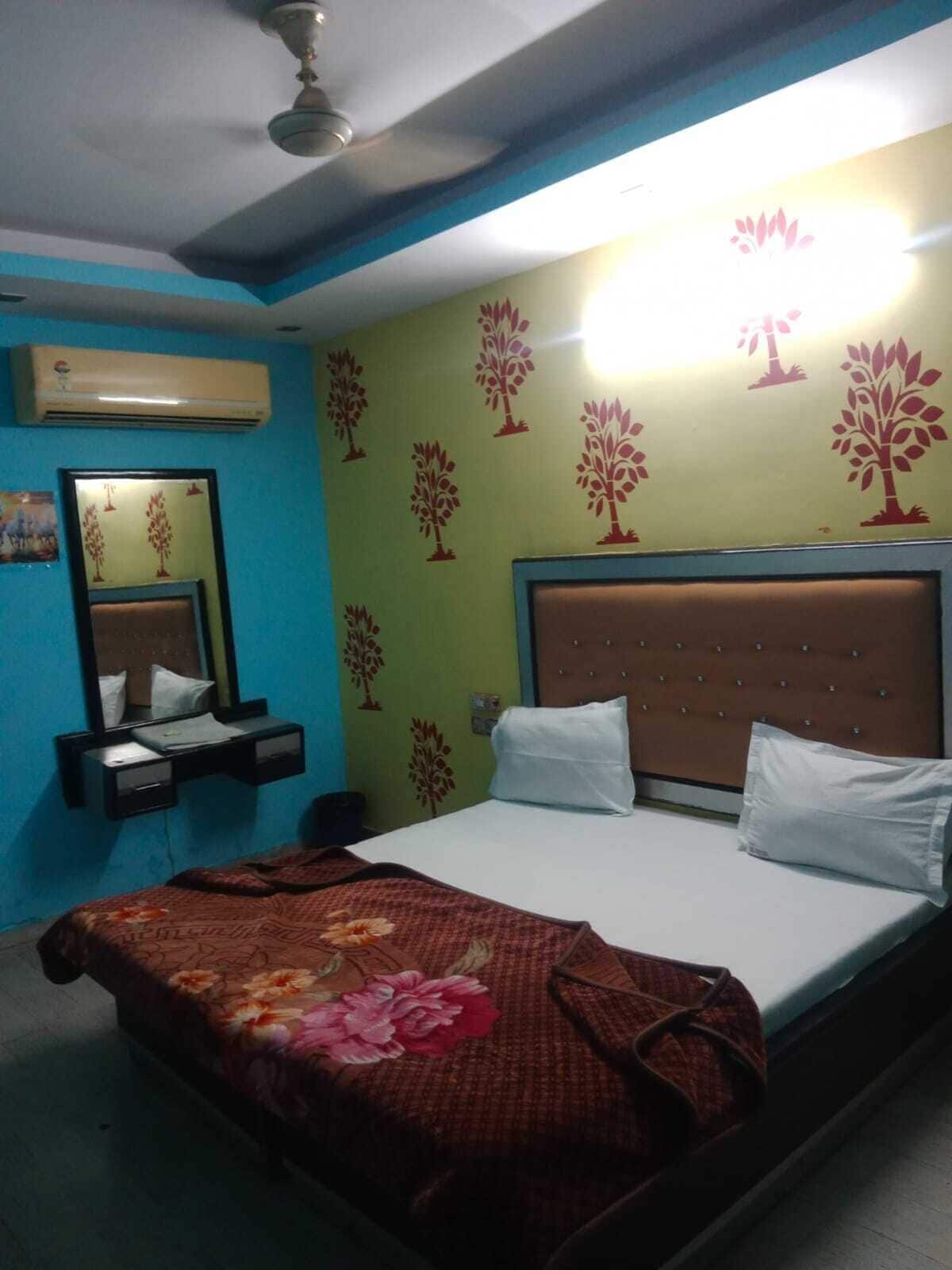 Una habitación de hotel con una cama, una mesita de noche, un espejo y una pared decorada con motivos de árboles.