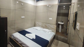 Ein modernes Hotelzimmer mit Bett, Deckenventilator, Badezimmer mit Waschbecken und Spiegel.