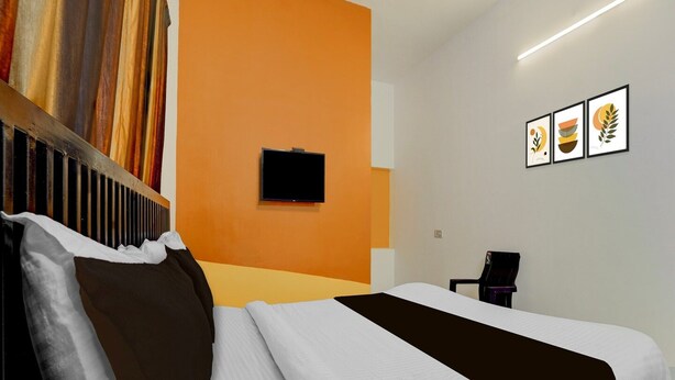 A hotel room with a bed, a television on the wall, and a chair. - Hotel O Auroville Bird Sanctuary Chennai (Vanur)