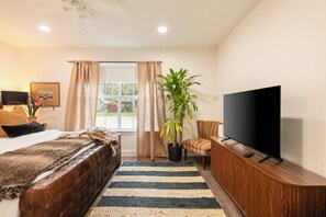 A hotel room with a bed, a TV, a plant, and a window with curtains. - Walk to Historic Georgetown Square: Texas Getaway! (Georgetown)