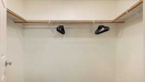 Ein Schrank mit einer Holzstange und zwei schwarzen Kleiderbügeln.