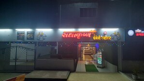 A restaurant with a neon sign, outdoor seating, and a vending machine. - Hotel Radhakrishna (Neral)