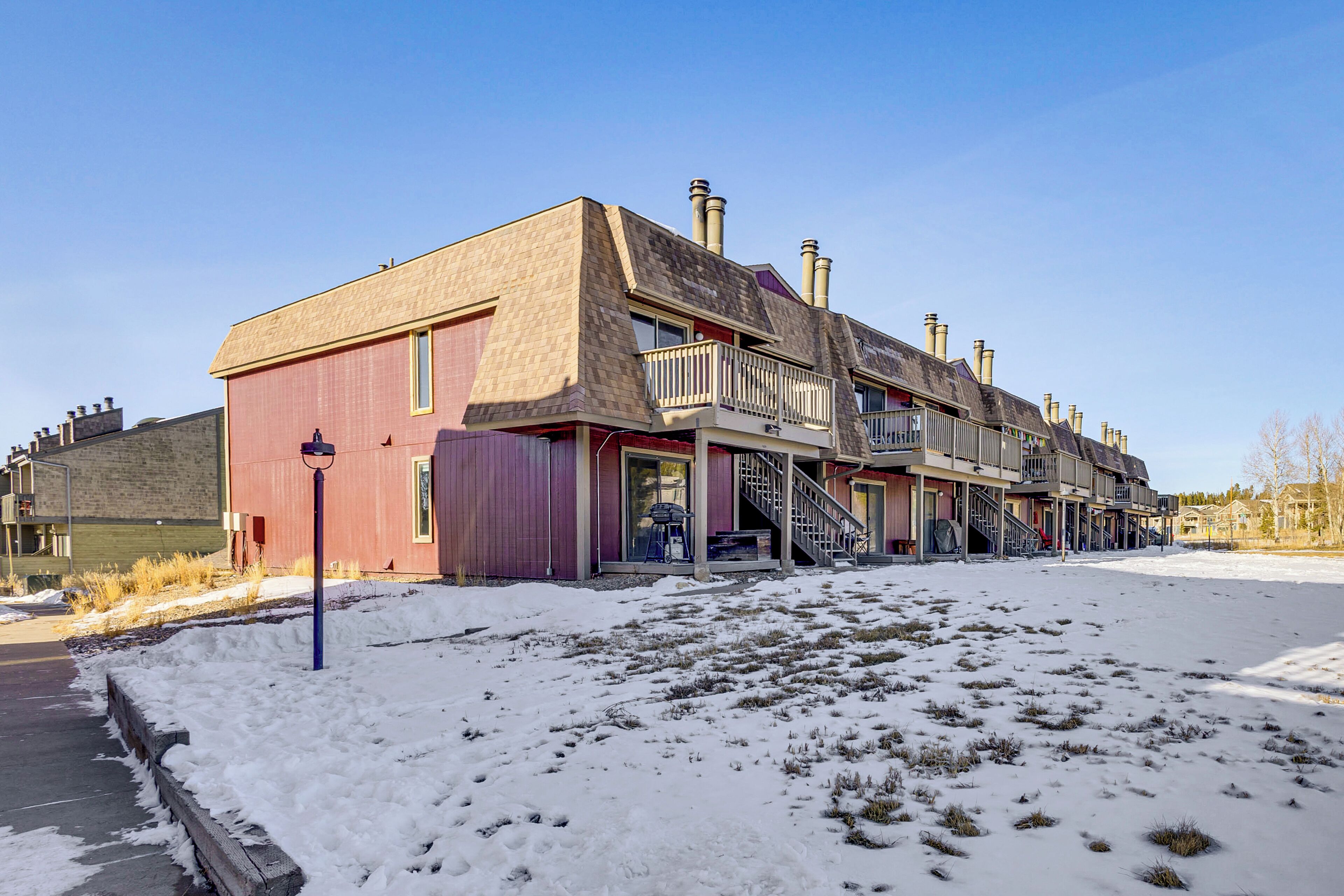Ein mehrstöckiges Gebäude mit roter Fassade, mehreren Schornsteinen und einem Balkon im zweiten Stock.