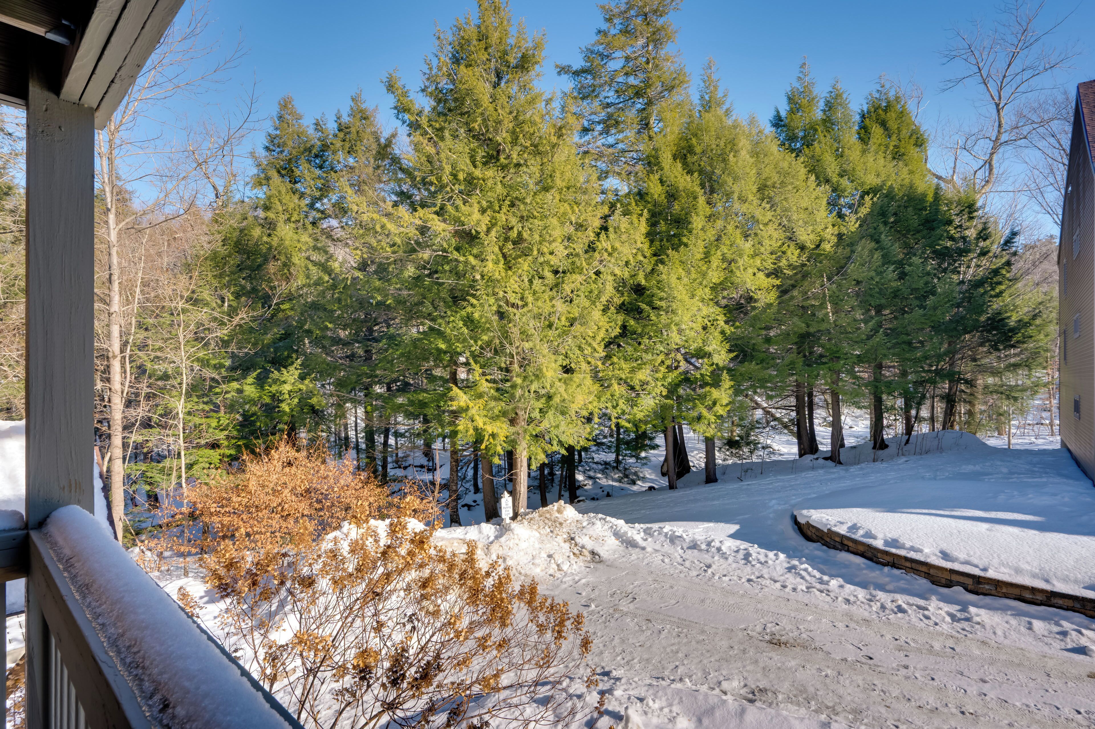 A snowy landscape with a wooden deck and a building in the background.