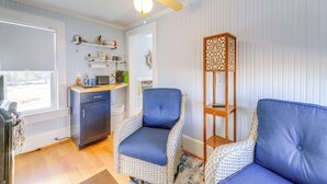 Ein Zimmer mit Korbmöbeln, einem Deckenventilator, einem Fenster und einer Küchenzeile.
