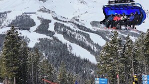 Un asiento de telesilla suspendido sobre una montaña nevada con cielo despejado.