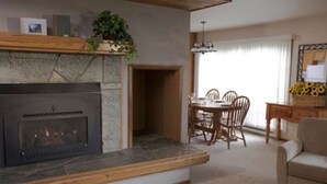 Una sala de estar con chimenea, un comedor con mesa y sillas, y un sofá.