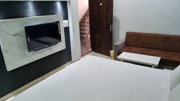 Een kamer met een ingebouwde oven, een bank, een klein tafeltje en een trap op de achtergrond.