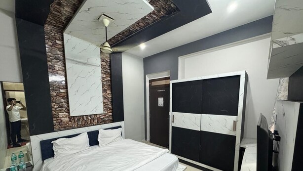 A modern bedroom with a bed, a wardrobe, a mirror, and a television. - Gokul Hotel (Malpura)