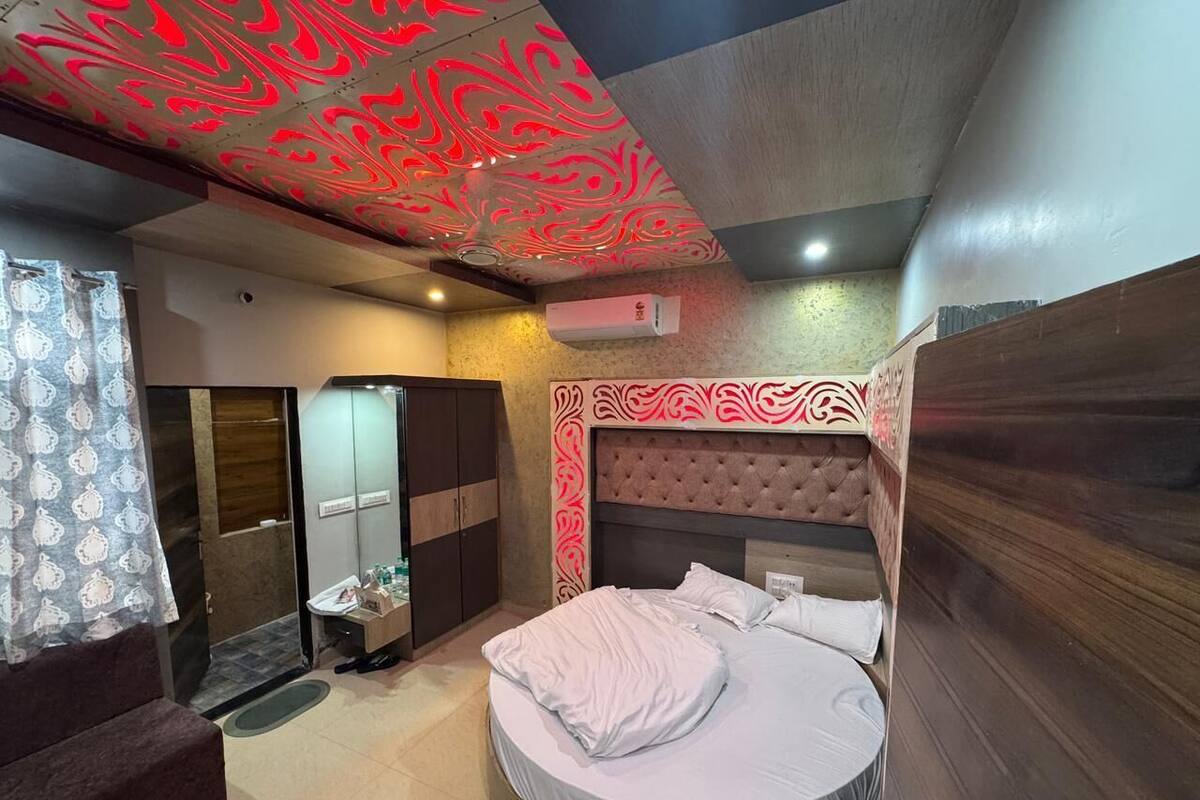 Een slaapkamer met een rond bed, een kaptafel met spiegel, een kledingkast en een plafond met een abstract rood ontwerp.