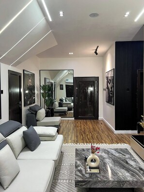 A modern living room with a sofa, a coffee table, and a large mirror. - EAGLES HOTEL AND APARTMENT (Abuja)