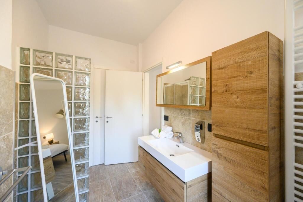 Un bagno moderno con uno specchio grande, un mobile bagno in legno e un box doccia in vetro.