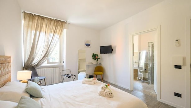 Hotelkamer met een groot bed, een bureau, een stoel, een televisie en een badkamer die door een open deur zichtbaar is.
