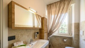 Een moderne badkamer met een grote spiegel, een wastafel, een toilet en een douchehoek.