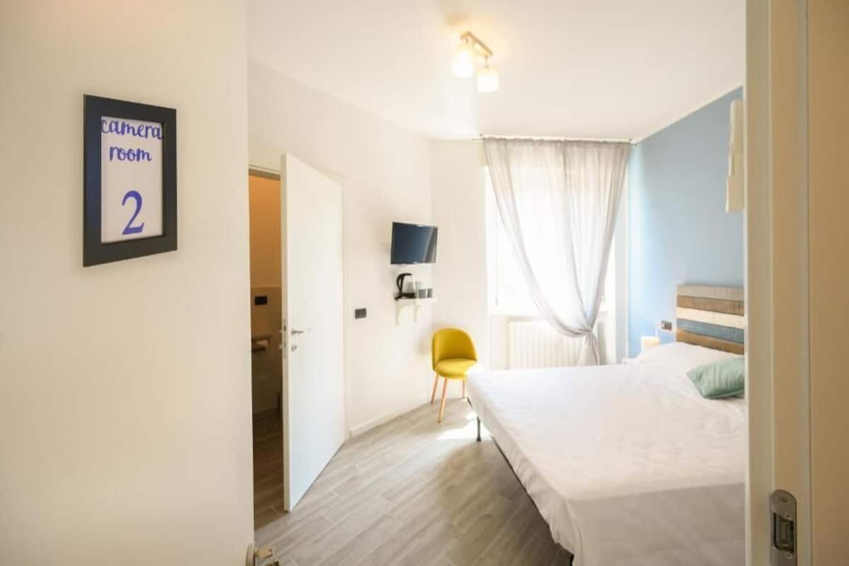 Une chambre à coucher comprenant un lit, un téléviseur, une chaise et un panneau indiquant qu’il s’agit d’une salle de contrôle vidéo.