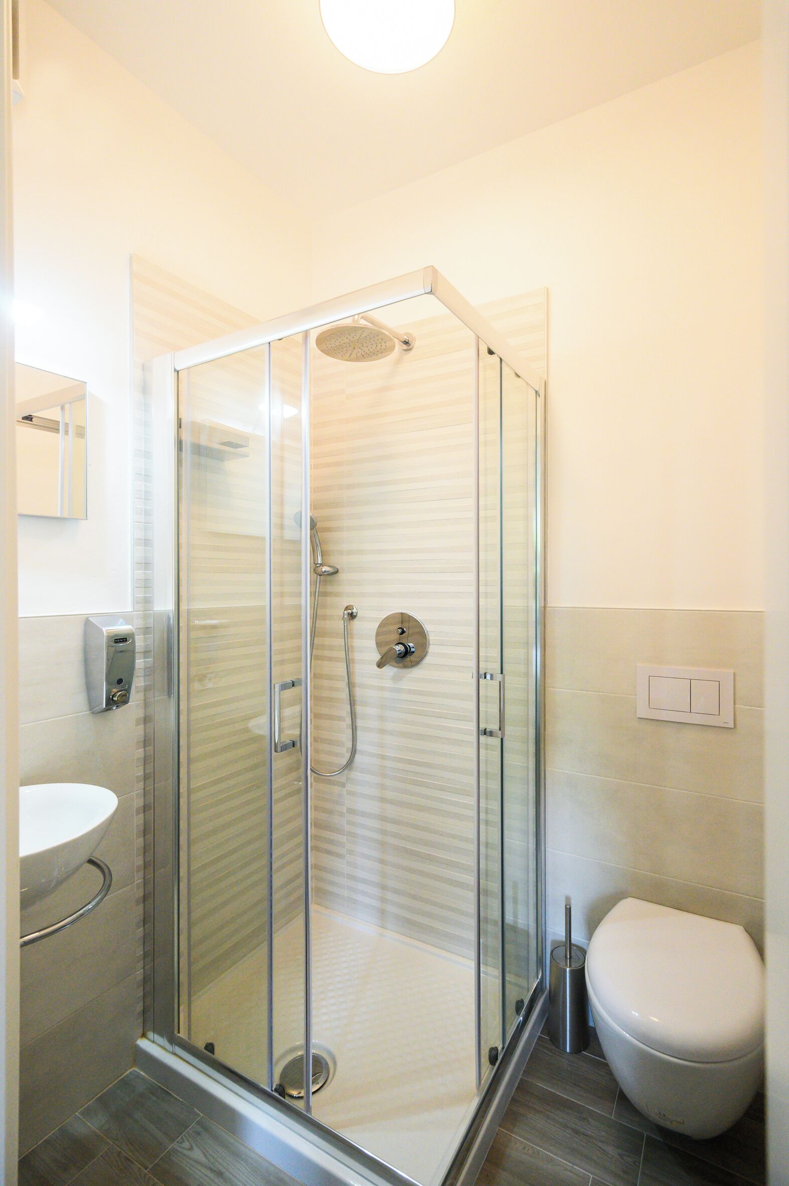 A modern bathroom with a glass-enclosed shower, a toilet, and a sink.