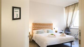 Un dormitorio ordenado con cama, mesita de noche, lámpara y un letrero que indica una sala de cámaras.
