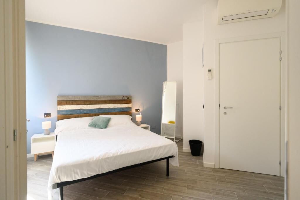 A bedroom with a bed, bedside tables, a nightstand, a mirror, and a door.